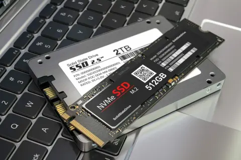 Dwa dyski SSD: 2.5-calowy 2TB i smukły M.2 512GB, leżą na klawiaturze laptopa. To nowoczesne rozwiązania, które pokazują, co to SSD.