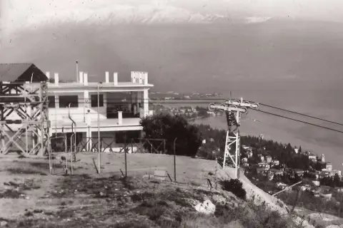 Stazione della funivia con vista panoramica su San Michele Salò e il lago. Montagne innevate sullo sfondo.