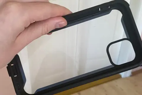 Dłoń trzyma czarne etui na telefon z przezroczystym tyłem. Dowiedz się, jak wyczyścić etui na telefon, aby wyglądało jak nowe.