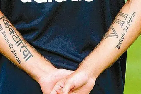 Brazos de Haidar Juma con tatuajes: "Victoria" en sánscrito y "Perfectio In Spiritu" en latín.