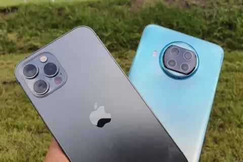 Porównanie aparatów: iPhone (iOS) kontra Xiaomi (Android). Dwa smartfony na tle zielonej trawy.