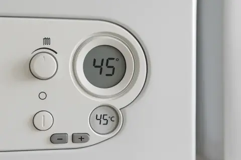 Panel sterowania kotła De Dietrich. Cyfrowy wyświetlacz pokazuje 45°C. Pokrętło i przyciski do regulacji ogrzewania.