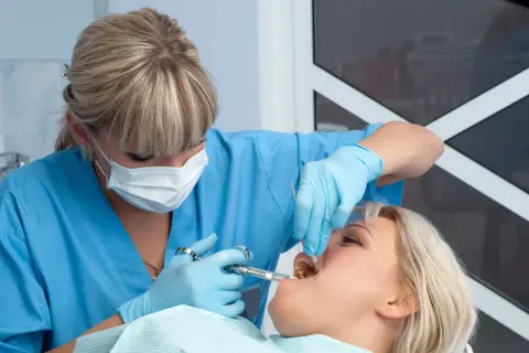 Dentista somministra anestetico per mal di denti a una paziente.