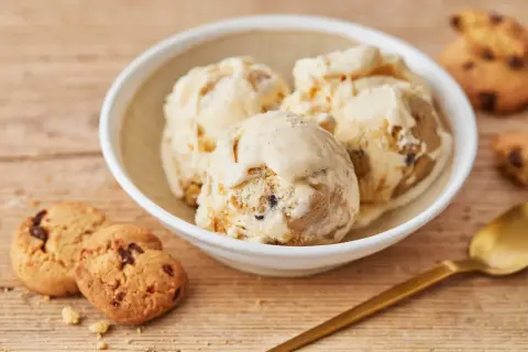 Schüssel mit cremigem Cookie Dough Eis, daneben Kekse und Löffel. Perfekt, um Cookie Dough Eis selber machen zu lernen.