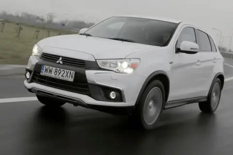 Biały Mitsubishi ASX 1.6 benzyna na mokrej drodze, z widocznym numerem rejestracyjnym WW 892XN.