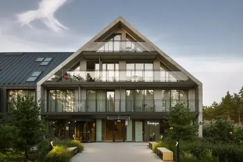 Nowoczesny budynek hotelowy Saltic Resort & Spa Łeba z betonową fasadą i przeszklonymi balkonami.