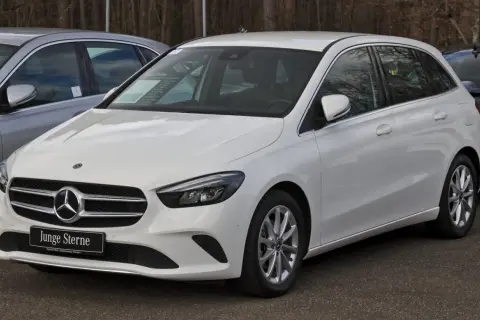Biały mercedes hatchback z tabliczką "Junge Sterne" na grillu, gotowy do jazdy.