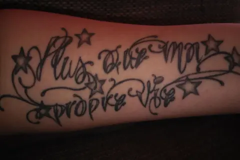 Dezentes Tattoo mit Kindesnamen für einen Mann, verziert mit Sternen und Schnörkeln.