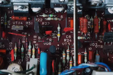 Wnętrze wzmacniacza samochodowego z widocznymi rezystorami, kondensatorami i innymi elementami elektronicznymi. To zdjęcie może pomóc zrozumieć, jak podłączyć wzmacniacz samochodowy.