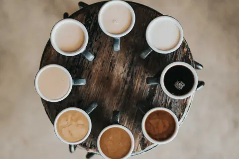 Åtta koppar kaffe i olika nyanser, från mörk espresso till ljus latte. En visuell guide till skillnad mellan latte och cappuccino.