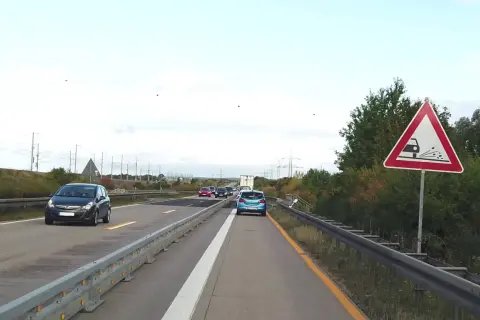 Achtung, stau schild warnt vor schleudernder Fahrbahn. Autos fahren auf der Autobahn.