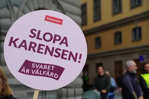 En demonstration mot karensdag regler. Skylten lyder "Slopa karensen! Svaret är välfärd" och bär Kommunals logotyp.