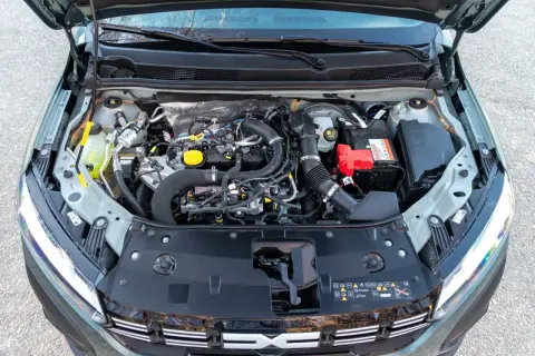 Vista del motor de un Dacia Sandero Stepway. Se aprecian componentes como la batería, el depósito de refrigerante y el sistema de admisión de aire.