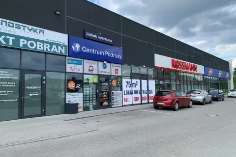Budynek z szyldami "Diagnostyka", "Centrum Podróży", "Unilink Ubezpieczenia" i "Rossmann".
