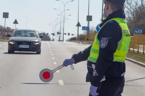 Policjant kieruje ruchem, zatrzymując samochód. Może to być kontrola drogowa lub kurs reedukacyjny.