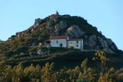 Edificio blanco con tejado rojo en la ladera rocosa del Pico Sacro.