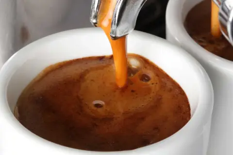 Caffè espresso che scende lentamente nella tazzina, creando una crema densa e invitante. Un piacere per gli occhi, se il caffè scende troppo piano, forse è ora di un caffè più forte.