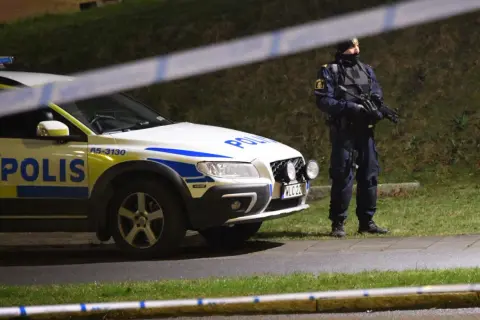 Polisbil och beväpnad polis, kanske Sandra Litzell, vid en avspärrning.
