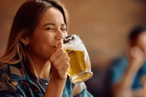 Donna sorridente beve una weizen beer in un pub.