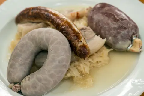 Eine bayerische Schlachtschüssel mit Blutwurst, Leberwurst und Bratwurst auf Sauerkraut.