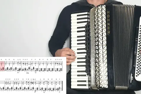 Akordeonista gra "Sto lat", nuty literowe pokazują melodię.