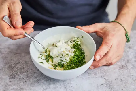 Ein cremiger Knoblauchdip mit frischer Petersilie wird zubereitet, perfekt als Beilage zu Flammlachs.