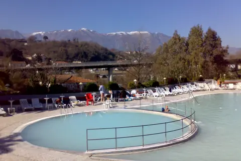 Piscine termali con lettini e ombrelloni, montagne innevate sullo sfondo. Un'oasi di relax per godersi le contursi terme gratis.
