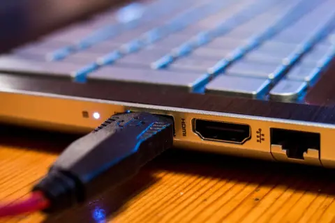 Podłączanie monitora do laptopa przez HDMI. Wtyczka kabla w porcie laptopa.