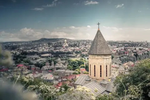 Widok na Tbilisi z kościołem w pierwszym planie. Marzysz o podróży? Sprawdź, ile trwa lot do Gruzji!