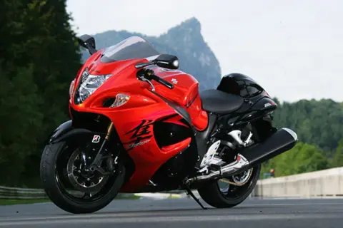 Czerwono-czarny motocykl Suzuki Hayabusa 1300 na drodze, z górami w tle.
