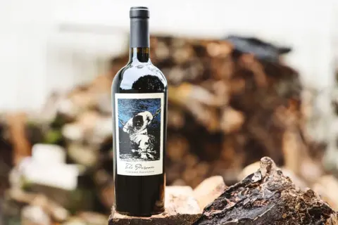 En flaska "The Prisoner" Cabernet Sauvignon står på en träbit. Etiketten visar en hund i kedjor, vilket ger en hint om hur detta vin kan kallas.