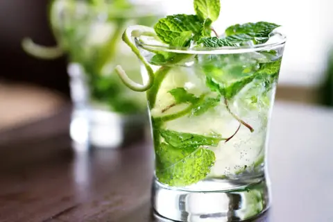 Un verre de virgin mojito rafraîchissant, rempli de glaçons, menthe fraîche et rondelles de citron vert.