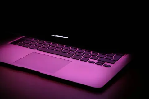 Klawiatura MacBooka w różowym świetle. Chcesz wiedzieć, jak zrobic @ na macbook? To proste: Option + 2.