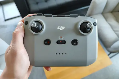 Dłoń trzyma szary kontroler DJI, gotowy do sterowania dronem.