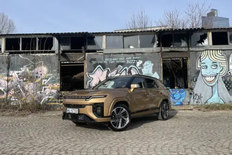 Złoty SsangYong Actyon na tle zniszczonego budynku z graffiti.