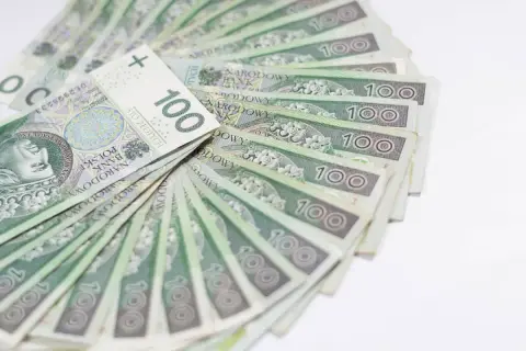 Stos stuzłotowych banknotów, ułożonych wachlarzowo. Idealne na świadczenie urlopowe, by odpocząć i cieszyć się wolnym czasem.