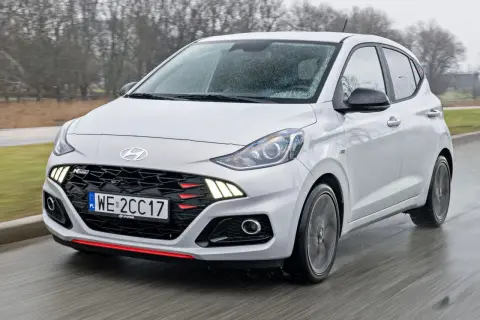 Biały Hyundai i10 N Line w ruchu, z widoczną kratką i światłami LED. Sprawdź aktualną hyundai i10 cena.