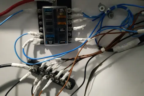 Panel de fusibles con cables conectados, ilustrando la diferencia entre disyuntor y magnetotérmico en un sistema eléctrico.