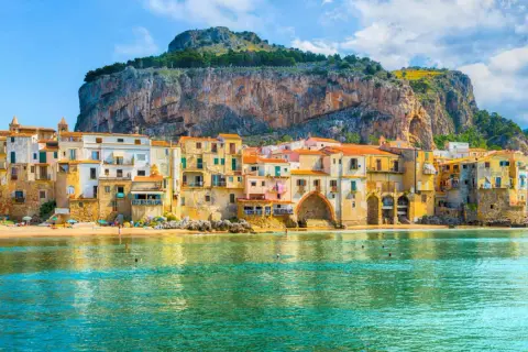 Case colorate affacciate sul mare di Cefalù, con la Rocca a dominare lo sfondo.