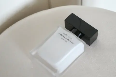 Elegancka butelka perfum Narciso Rodriguez Pure Musc for her, z czarną nakrętką, na jasnym tle.