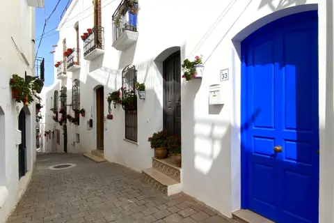 Calle empedrada con casas blancas y puertas azules vibrantes. Un lugar perfecto para descubrir qué hacer en Mojácar.