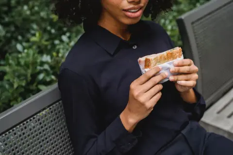 Frau hält Sandwich, wie bei der Sandwich-Methode für Feedback.