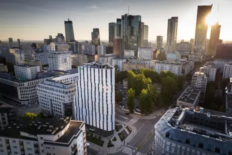 Widok na miasto z nowoczesnym budynkiem Holiday Inn Twarda w centrum. W tle wieżowce i zieleń.