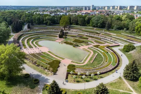 Widok z lotu ptaka na park Cytadela z jeziorem, tarasami i alejkami. W tle zabudowania miejskie.