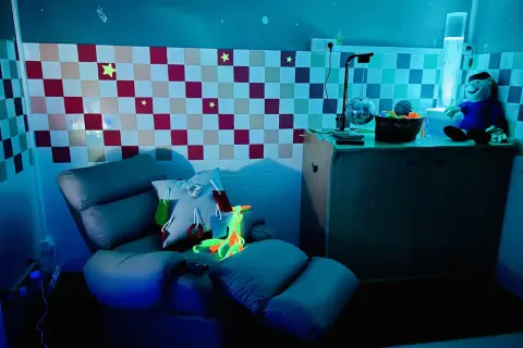 Chaise confortable et lumineuse pour une séance snoezelen, avec des étoiles au mur et une colonne à bulles.