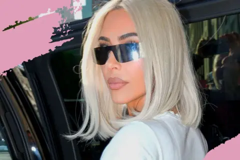 Frau mit platinblonden Haaren und futuristischen Sonnenbrillen steigt aus einem Auto.
