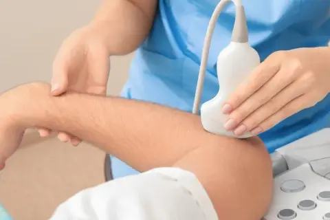 Badanie usg tkanek miękkich łokcia. Lekarz przykłada głowicę aparatu USG do przedramienia pacjenta.