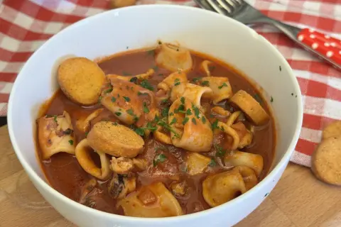 Un invitante piatto di moscardini in umido, ricchi di sapore e guarniti con prezzemolo fresco, accompagnati da crostini dorati.