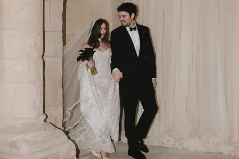 Novia con velo y ramo de **stella banderas** negras, y novio de traje, saliendo de una iglesia.