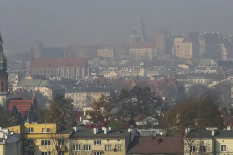 Mglisty widok Krakowa z wieżą kościelną i zamkiem. Warto wiedzieć, jak chronić się przed zanieczyszczeniami powietrza w takich warunkach.